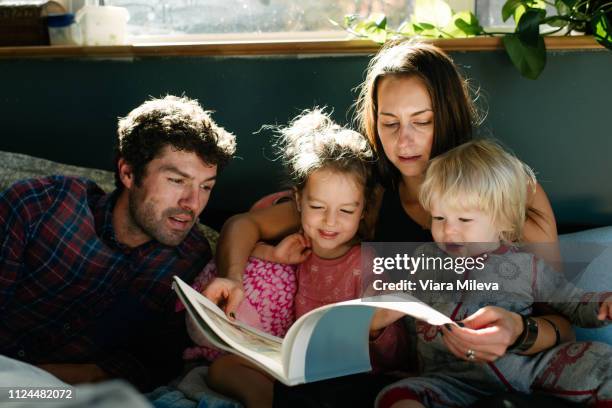 parents reading to children in bed - couché de soleil photos et images de collection