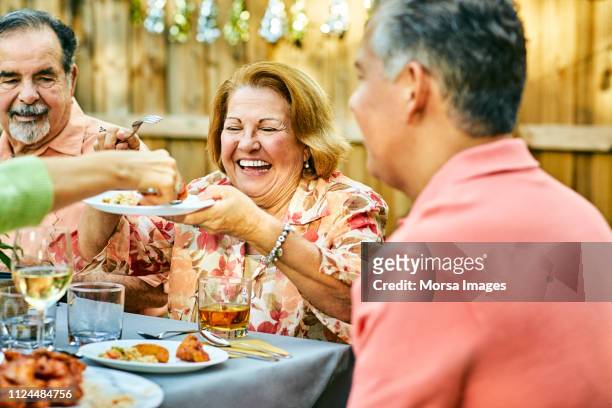 cheerful family eating at table in back yard - candid mature couple outdoors stock-fotos und bilder