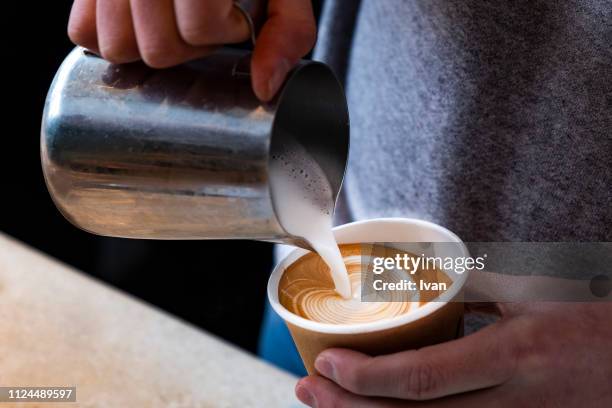 man hands holding fresh coffee or latte art in a cup at coffee shop and restaurant, bar or pub - coffee machine stockfoto's en -beelden