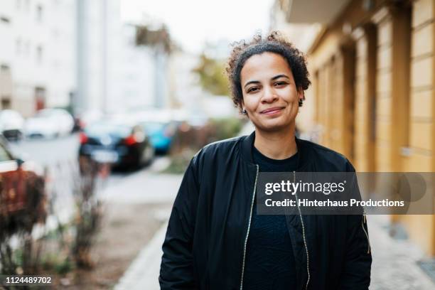 portrait of stylish young woman smiling - black jacket photos et images de collection