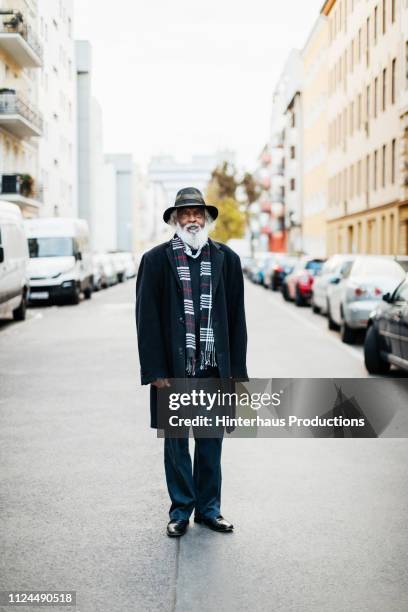 portrait of mature man standing in street - black coat stock-fotos und bilder