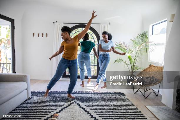 women friends having fun at home dancing and singing in the living room - friends home stock pictures, royalty-free photos & images