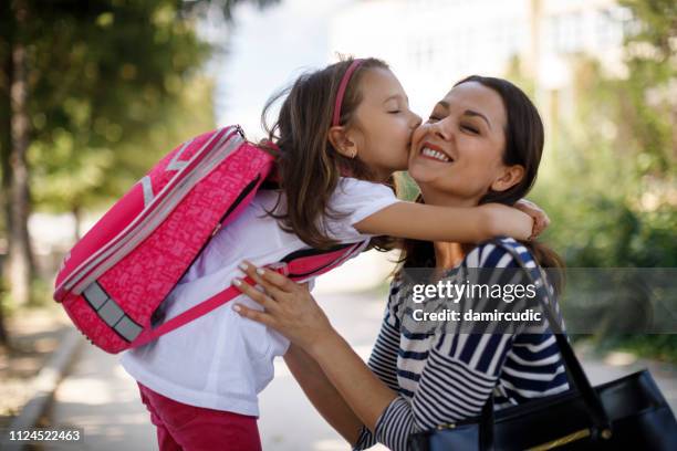 dochter moeder kussen voor school - eerste-schooldag stockfoto's en -beelden
