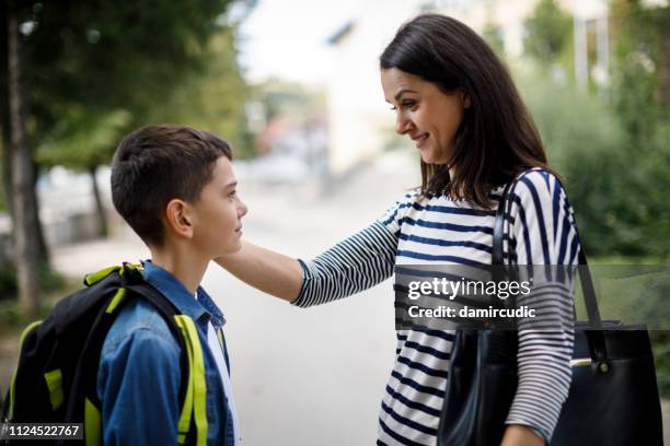 madre saluta figlio davanti a scuola - leaving school foto e immagini stock