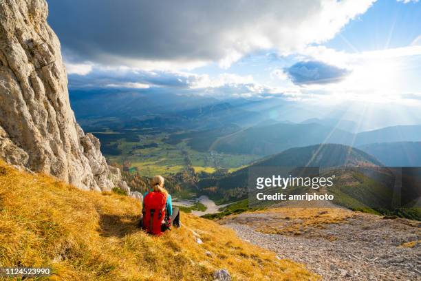 solo traveler back view sporty mountaineer woman resting high up in mountains - mountain range stock pictures, royalty-free photos & images