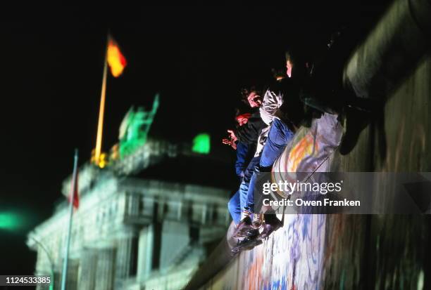 teenagers sitting on the berlin wall, near the brandenburg gate, after the opening of the wall in november 1989 - ベルリンの壁 ストックフォトと画像