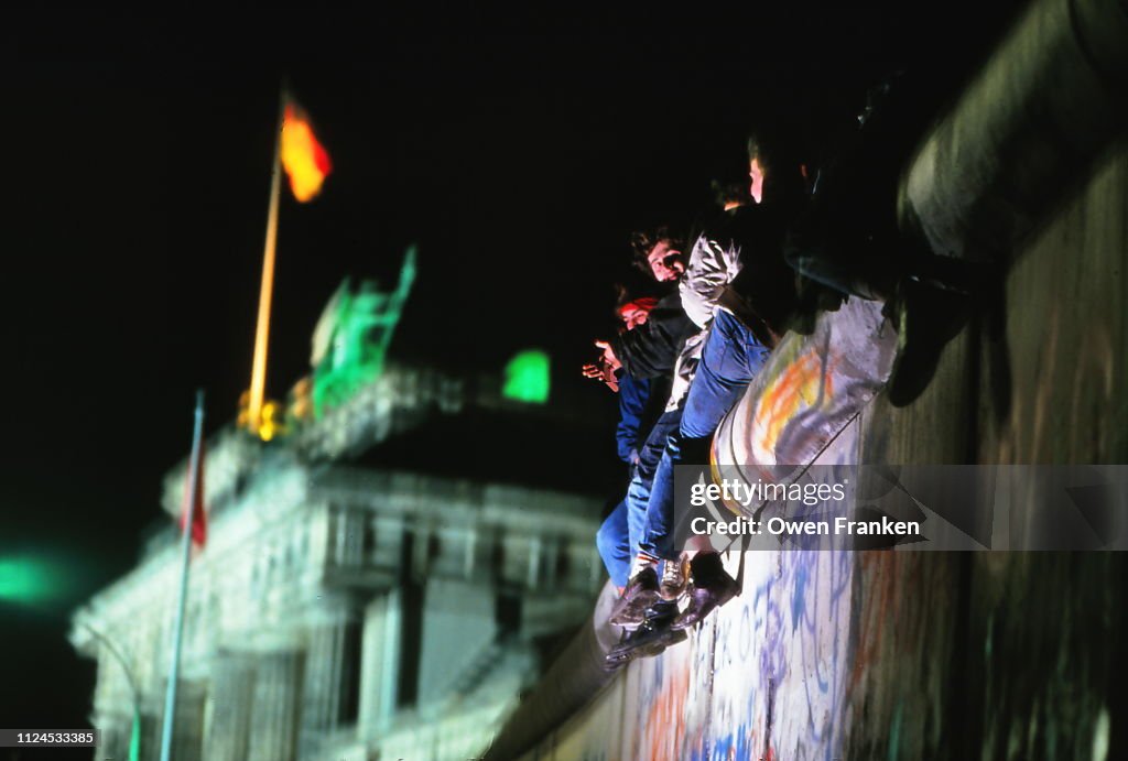 Teenagers sitting on the Berlin Wall, near the Brandenburg Gate, after the opening of the wall in November 1989