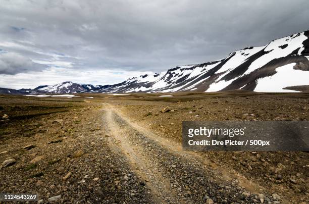 traveling down a gravel road in snowy mountains of iceland - kaldidalur stock pictures, royalty-free photos & images