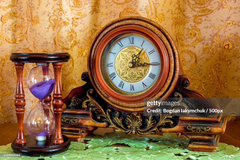 Photo Of An Old Clock And Sandglass On Brown Background
