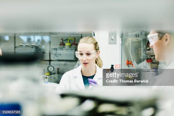 Female scientist discussing experiment with partner in laboratory