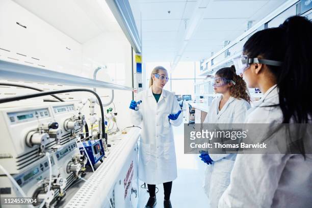 female scientist explaining experiment to colleagues in laboratory - plant stem stock-fotos und bilder