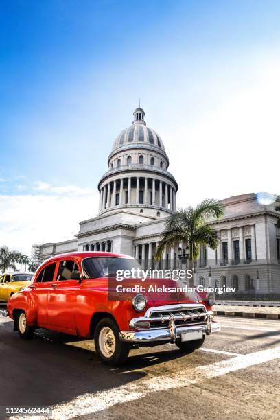 red vintage car in front el capitolio building in havana, cuba - el capitolio havana cuba stock pictures, royalty-free photos & images