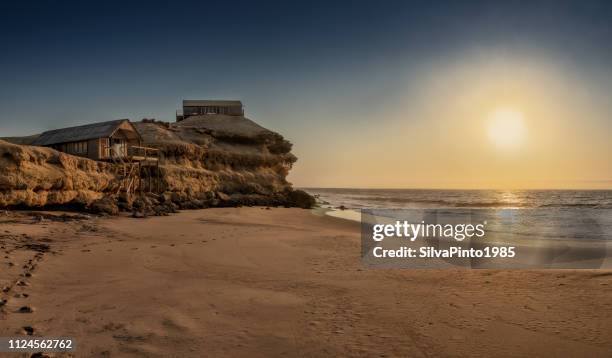 Beautiful sunset with cliff and wooden houses along the coast line of Namibe beach. Africa. Angola.
