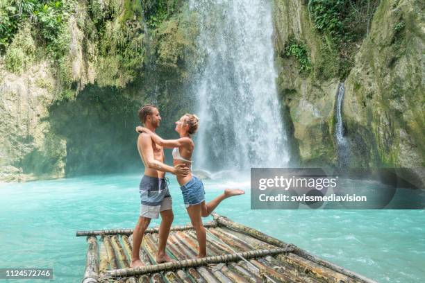 giovane coppia che contempla una bellissima cascata tropicale - bamboo raft foto e immagini stock