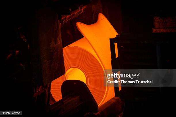 Glowing steel is rolled into flat steel in the hot rolling mill of ArcelorMittal Eisenhuettenstadt Germany Holding steel mill and rolled up as a coil...