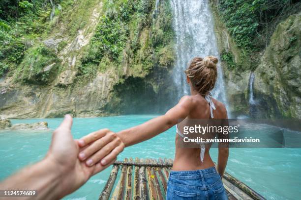 volg mij op concept jonge vrouw leidt vriendje naar idyllische waterval - veleiding stockfoto's en -beelden