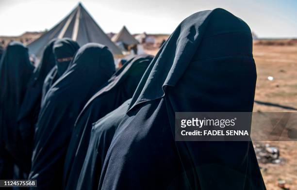 Fully veiled women fleeing from the Baghouz area in the eastern Syrian province of Deir Ezzor queue up on a field on February 12, 2019 during an...
