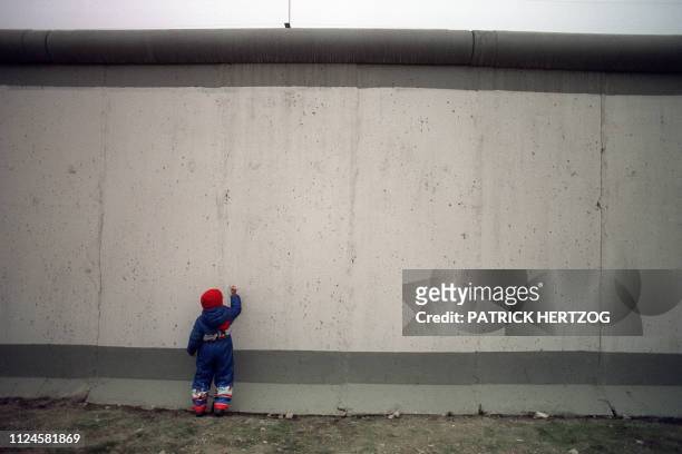 Young boy is trying to show his talent by drawing on the East side of the Berlin Wall, on November 21 a few yards from the newly-opened crossing at...