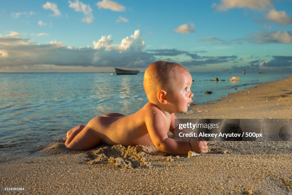 Side view shot of baby lying on beach