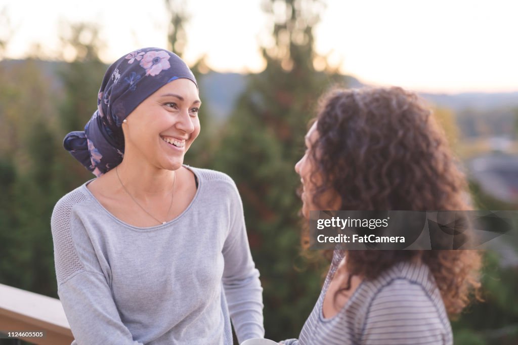 Schöne ethnische Frau kämpft gegen Krebs im Gespräch mit ihrer jüngeren Schwester