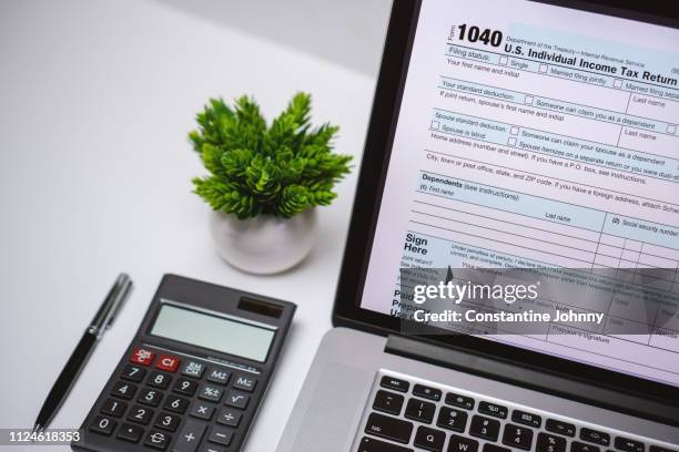tax form on laptop screen on work desk with pen and calculator - internal revenue service stock-fotos und bilder