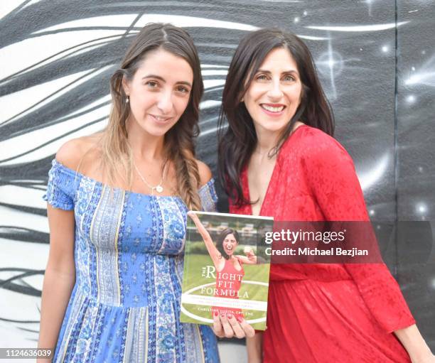 Lauren Francesca and Christine Lusita pose infront of artwork by Hans Haveron with her book "The Right Fit Formula" at TAP- Giveback Day on January...