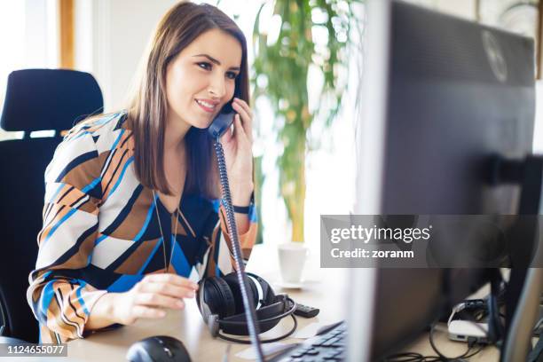 mujer de negocios hablando por teléfono fijo - teléfono con cable fotografías e imágenes de stock