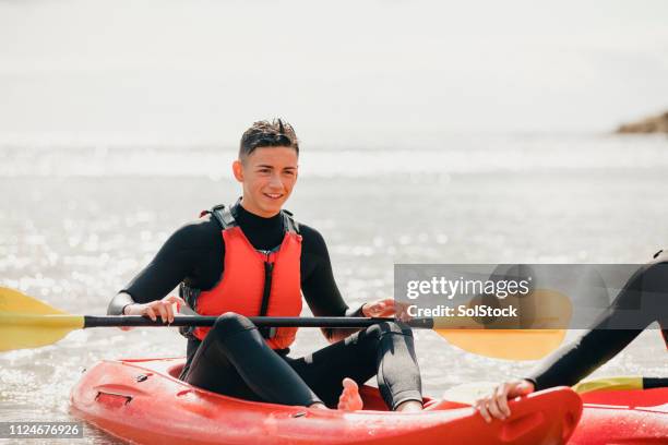 teenage boy enjoying time kayaking - teen boy barefoot stock pictures, royalty-free photos & images