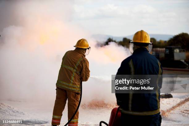 firemen training, firemen spraying firefighting foam at training facility - international firefighters day stock pictures, royalty-free photos & images