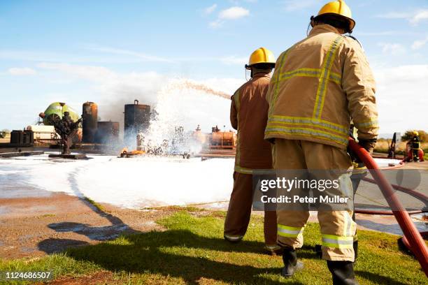 firemen training, team of firemen spraying firefighting foam at training facility - international firefighters day 個照片及圖片檔