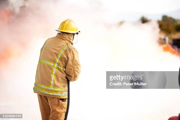 firemen training, fireman spraying firefighting foam at training facility - international firefighters day stock pictures, royalty-free photos & images