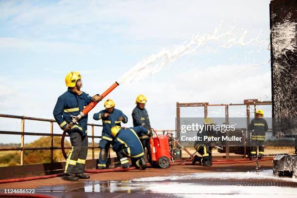 firemen training, firemen spraying firefighting foam at training facility - international firefighters day stock pictures, royalty-free photos & images