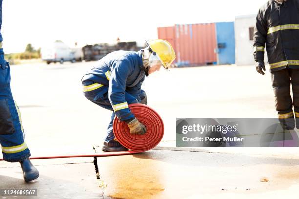 firemen training, fireman unrolling fire hose at training facility - international firefighters day 個照片及圖片檔