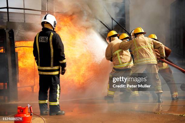 firemen training, firemen spraying water at fire at training facility, rear view - international firefighters day 個照片及圖片檔