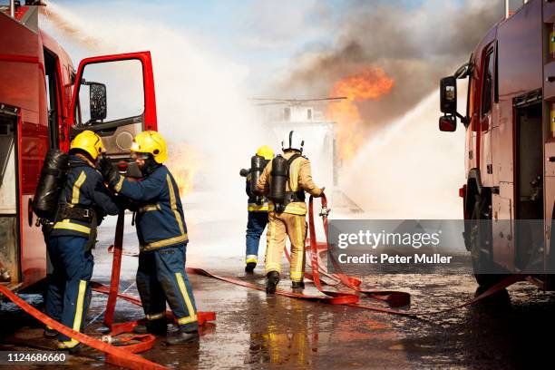 firemen training, team of firemen extinguishing mock helicopter fire at training facility - fireman uk stock pictures, royalty-free photos & images