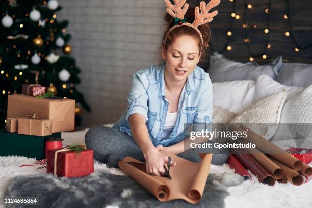 woman wrapping christmas presents on bed - daily life during christmas season in poland foto e immagini stock