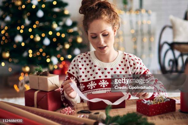 woman tying ribbon on christmas present - frau geschenk stock-fotos und bilder