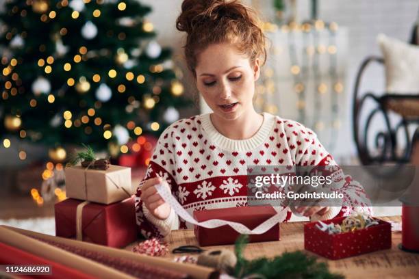 woman tying ribbon on christmas present - 包装紙 ストックフォトと画像