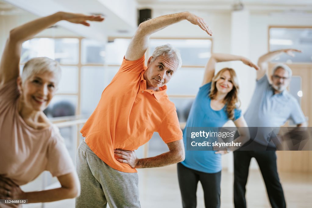 Group of senior people doing stretching exercises in health club.