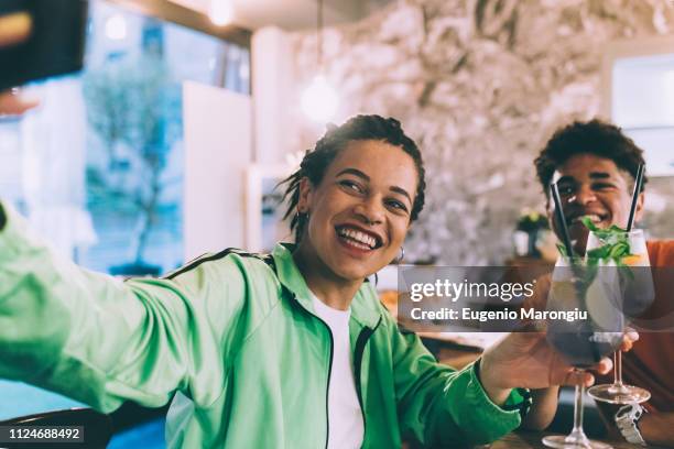 brother and sister taking selfie in bar - green pants fotografías e imágenes de stock