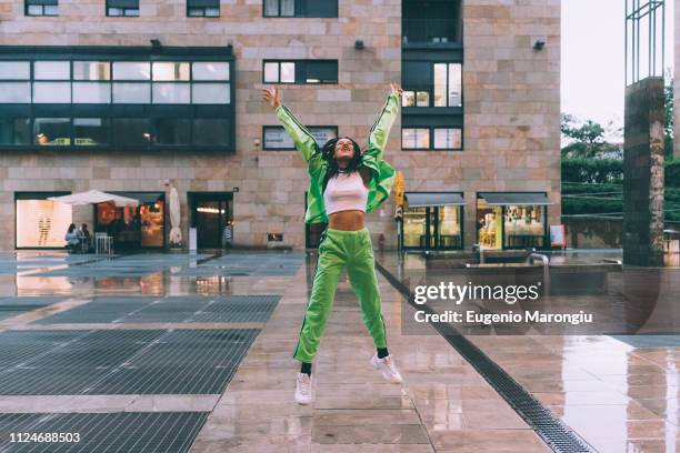 woman welcoming rain in town square, milan, italy - green pants fotografías e imágenes de stock