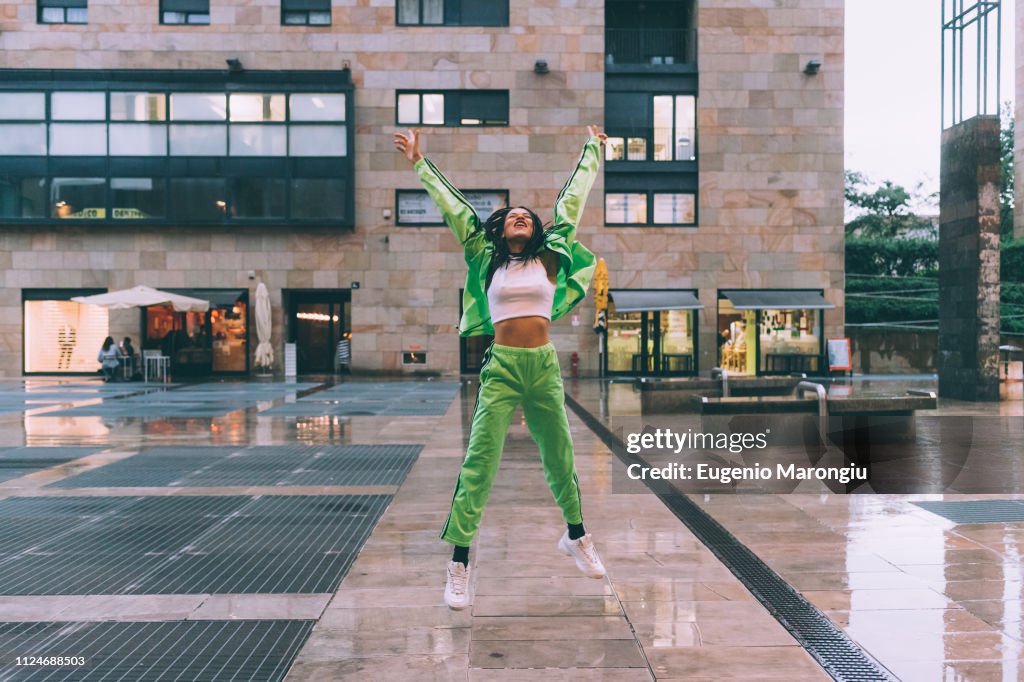 Woman welcoming rain in town square, Milan, Italy