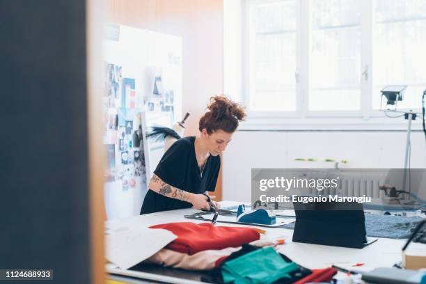 fashion designer cutting fabric from dressmaker's pattern - sarta foto e immagini stock
