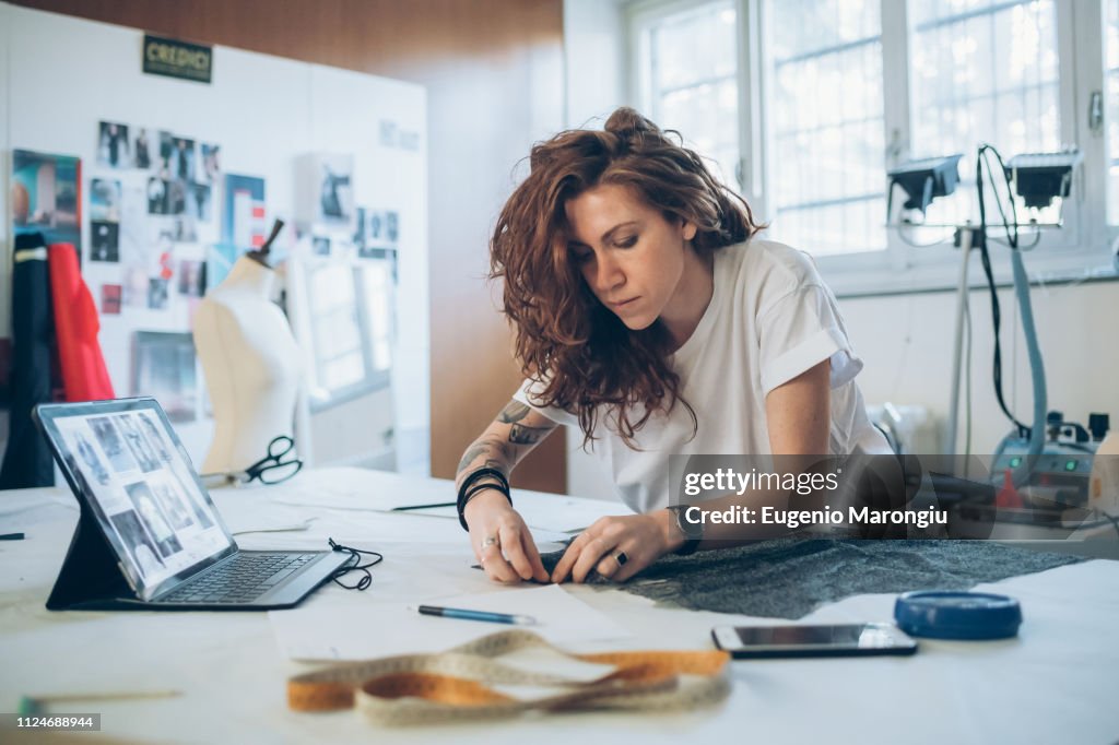 Fashion designer pinning fabric cutouts