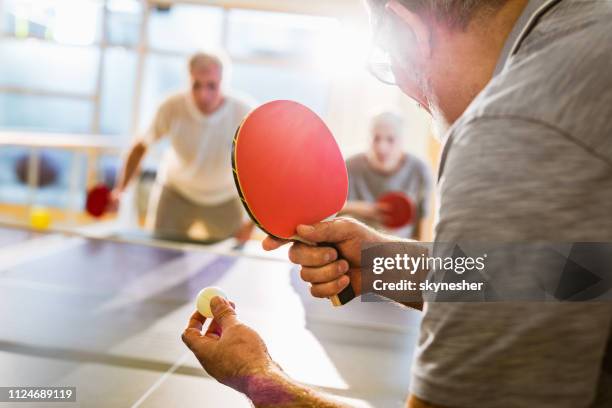 close up of senior man playing table tennis in health club. - table tennis stock pictures, royalty-free photos & images