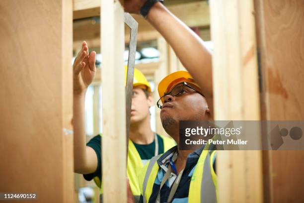 male higher education students building wooden framework in college workshop - male student wearing glasses with friends stock-fotos und bilder