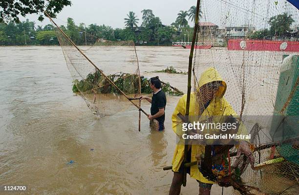 FiIlipinos cast their nets to catch fish for their meals in a flooded area July 13, 2002 in Marikina City, Philippines. Heavy rain from typhoon...