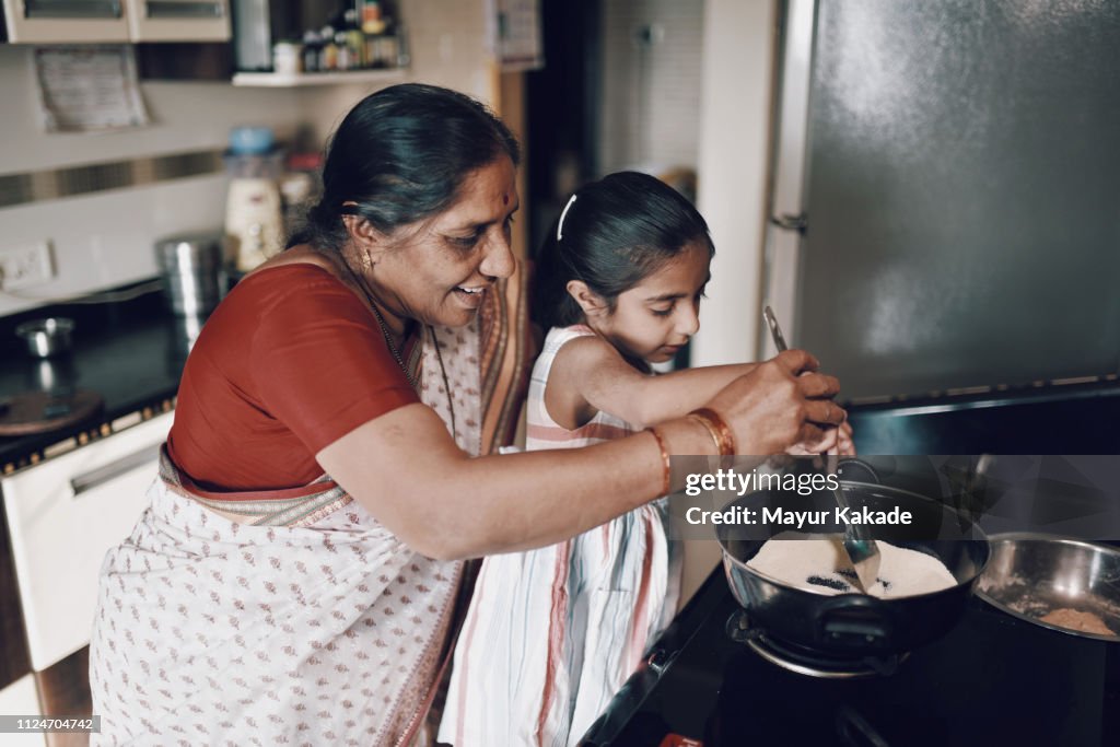 Young girl helping her grandmother while working in the kitchen