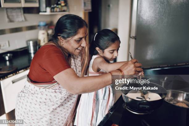 young girl helping her grandmother while working in the kitchen - asian granny pics 個照片及圖片檔