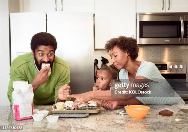 little girl home baking with her parents - cupcakes girls stock-fotos und bilder